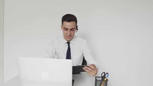 Office Manager with a Earset Provides Online Advice on a Laptop in Office