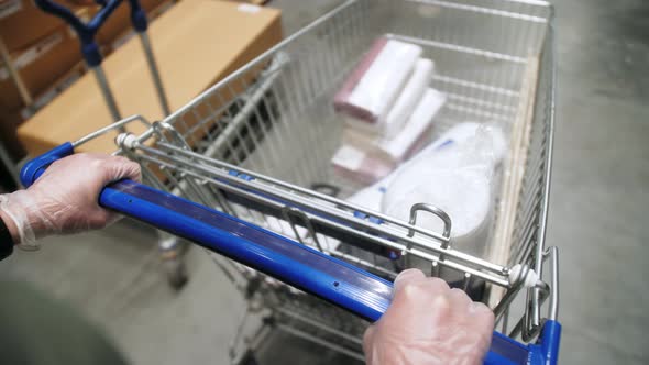 Hands of rubber gloves is pushing a shopping cart, Hands close up with shopping trolley. Shopping.