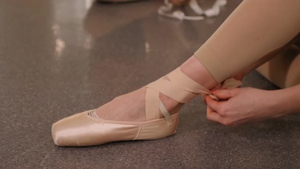 Close-up Young Ballerina Put on Pointe Shoes in Studio. Classical Dance School.