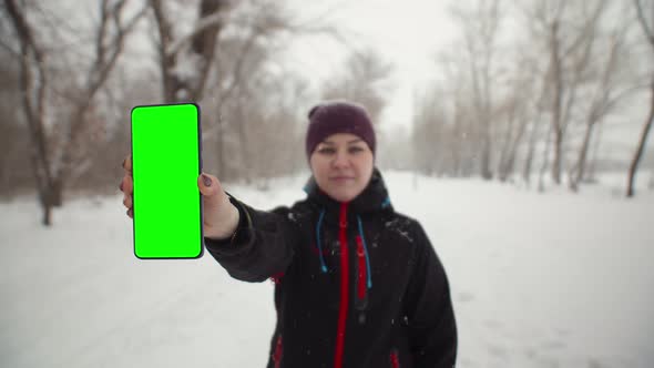 Woman Shows a Phone with Chromakey in Winter the Park