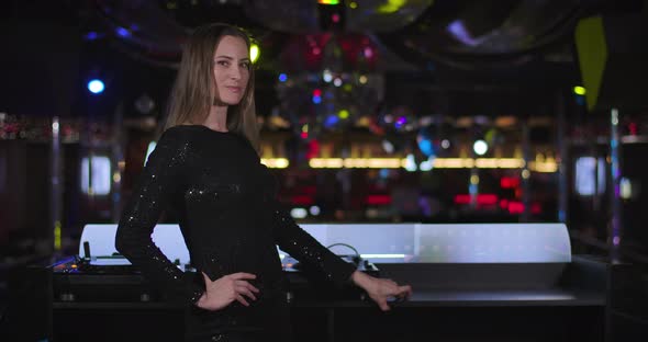 Portrait of Gorgeous Young Caucasian Woman in Black Dress Standing Next To Music Controller, Looking