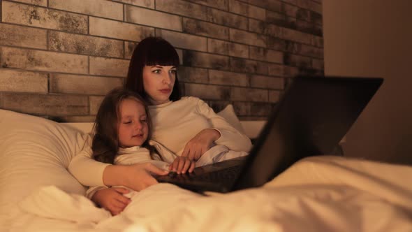 Excited Scared Family Mother and Little Funny Daughter Watching Movie on Laptop at Home