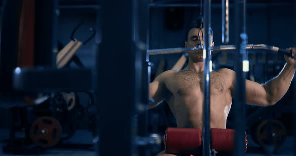 Bodybuilder Doing Exercise on the Simulator in the Gym