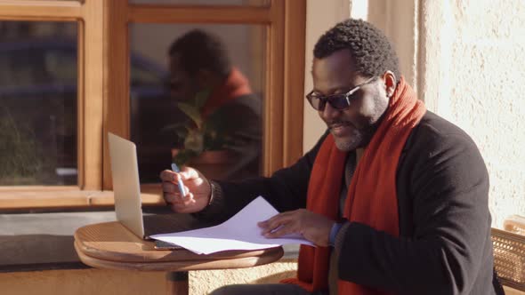 Smiling African man working with papers in cafe