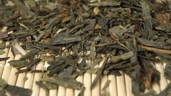 Dried Herbal Green Hemp Tea Leaves. Falling in slow motion onto a bamboo mat