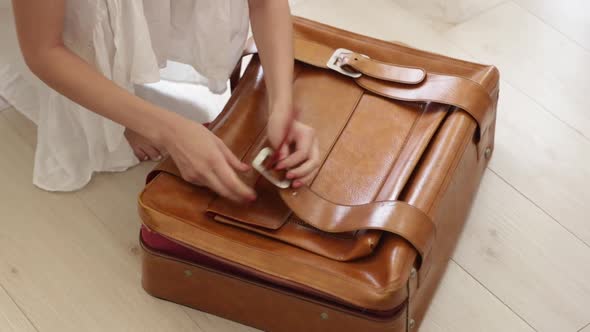 woman hands unlocked a belts on suitcase. Preparation for vacation