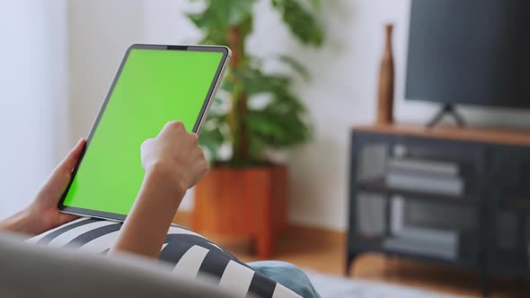 woman holding in hands a digital tablet with green screen for internet online.