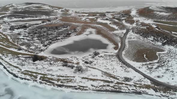 Frozen Landscape of Iceland, Aerial View. Ice on Lake, Road and Snow Capped Lava Fields on Cold Wint