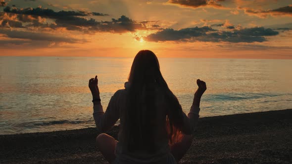 Back View of Woman Practicing Yoga in Meditation Pose on the Beach