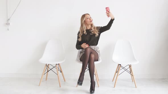 Smiling Blonde Woman Sitting on Office Chair. Young Assistant at the Workplace