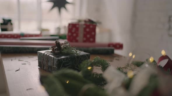 A Christmas Present Stands on a Wooden Table with Christmas Trees and Garlands