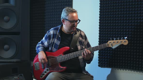 Musician Tuning Bass Guitar in Studio