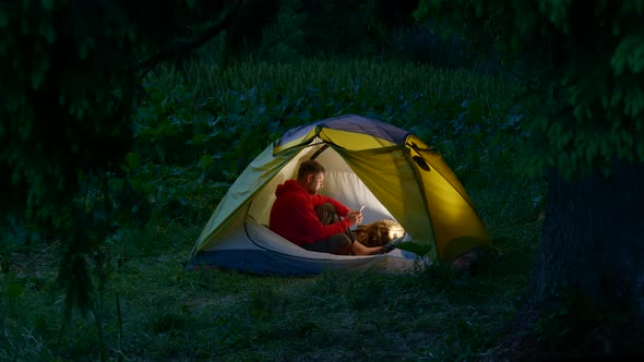 A Man in a Tent in the Night Forest