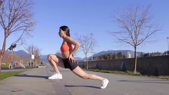 Athletic young woman stretching legs on curb