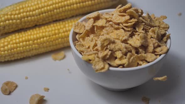 cornflakes fall into a bowl. corn cobs lie nearby. The concept of a healthy lifestyle