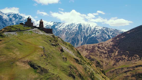 Scenic Drone Shot of Gergeti Trinity Church with the Caucasus Mountains in the Sunny Weather Kazbegi