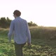 A farmer walks through a soybean field in the light of the sun's rays. - VideoHive Item for Sale