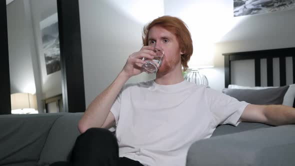 Relaxing Redhead Man Drinking Water While Sitting on Couch