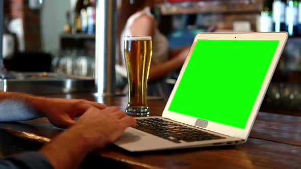 Customer using a laptop with green screen at bar counter