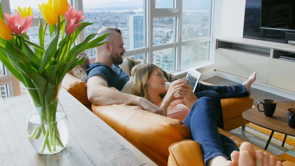 Couple using digital tablet and mobile phone in living room 4k