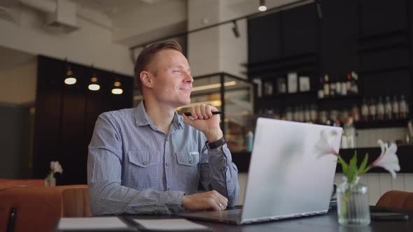 Thoughtful Serious Young Man Student Writer Sit at Home Office Desk with Laptop Thinking of