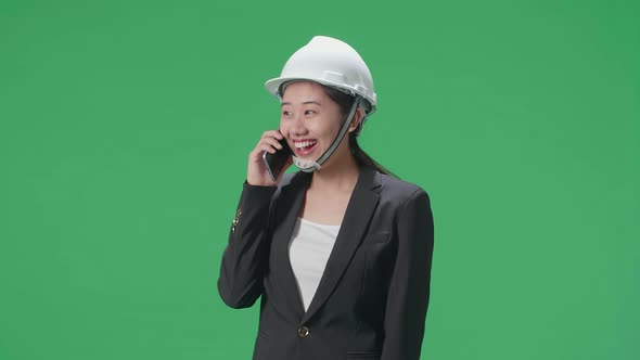 Smiling Asian Female Engineer Celebrating After Talking On Smartphone In The Green Screen Studio