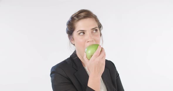 Woman biting and eating an apple on a white studio background