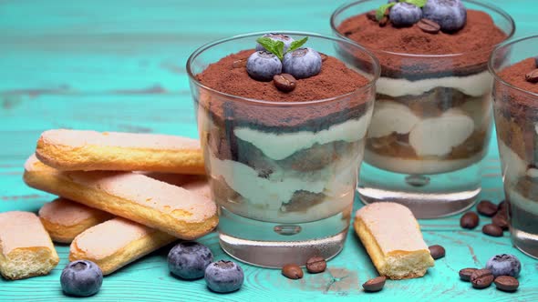 Classic Tiramisu Dessert in a Glass with Blueberries on Blue Wooden Background