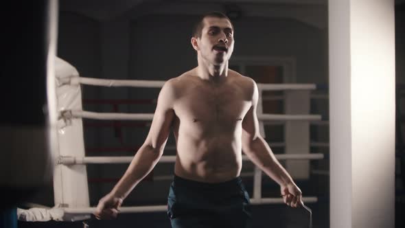 Box Training - a Man Standing on the Ring and Jumping Over the Jumping Rope