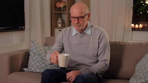 Happy Senior Man Drinking Tea at Home in Evening