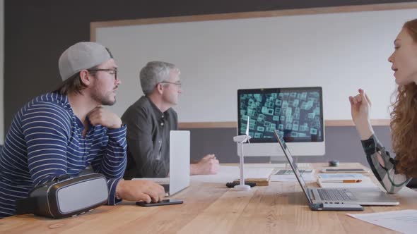 Two Caucasian men and woman working in a creative office