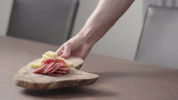 Slow Motion Man Put Olive Board with Vintage Cheese and Salae on Walnut Table