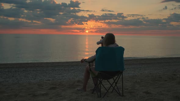 Back View of Woman Sitting on Camping Chair and Drinking Coffee