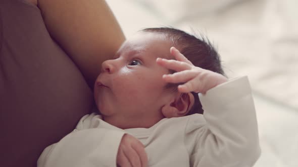 Newborn baby boy and his mother at home. Close-up portrait of the infant