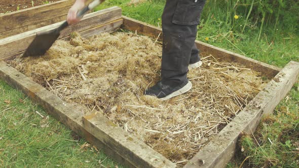 preparing raised garden bed with layered hay before adding soil