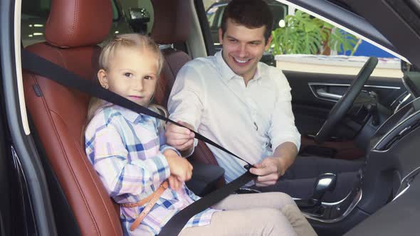 A Caring Father Fastens His Daughter's Seat Belts in the Car