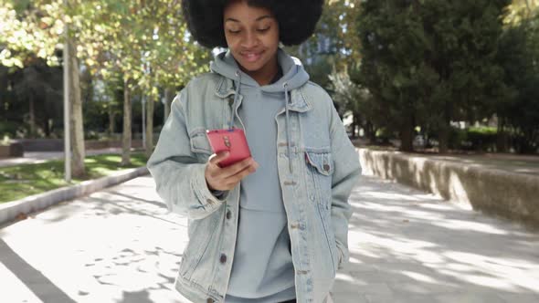 Young Woman Talking on Smart Phone While Walking in City Park