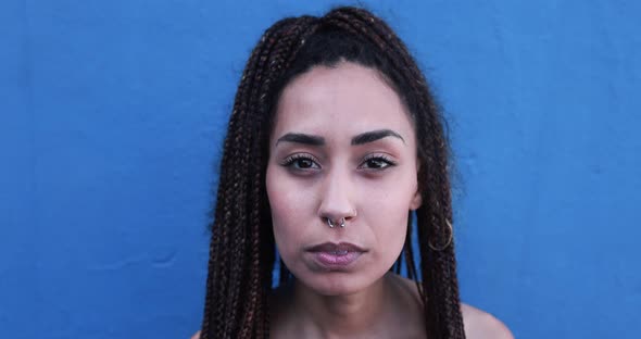 Mixed race girl looking serious on camera with blue background