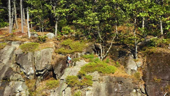 Aerial footage ORBIT around lone climber at the top of a cliff in Maine