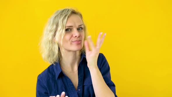 Crazy Cheerful Blonde Girl Licks Fingers After Tasty Eating Isolated on Yellow Studio Background