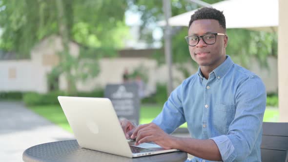 African Man with Laptop Smiling at Camera