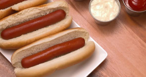 Appetizing plate of hot dogs with an assortment of sauces on the side.