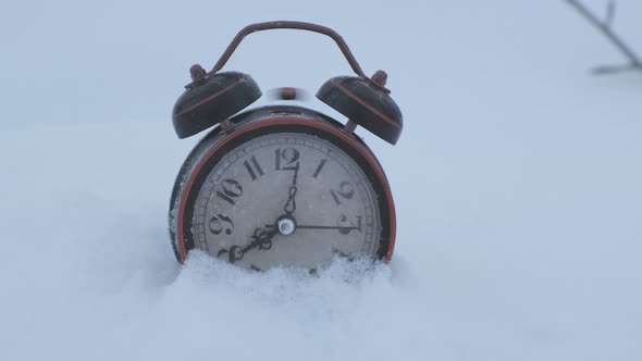 An old alarm clock rings at eight in the morning standing in the snow