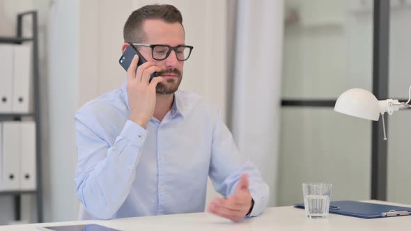 Middle Aged Man Talking on Smartphone at Work