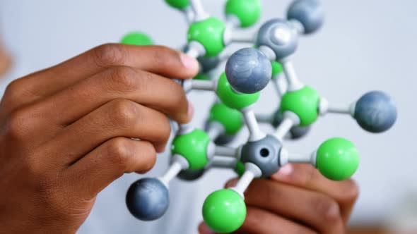 Schoolboy experimenting molecule model in laboratory at school