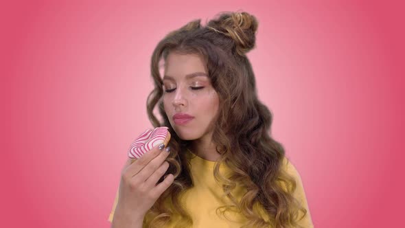 Attractive Girl with a Beautiful Styling Eats a Donut and Enjoys the Taste