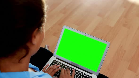 Female executive using laptop while sitting on wooden floor 4k