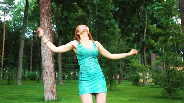 red haired girl in Holi paints dances in green park in slow motion