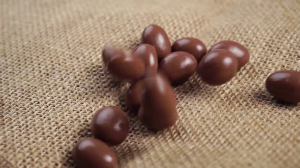 Chocolate coated glazed pistachio nuts fall in a heap on a rustic rough burlap