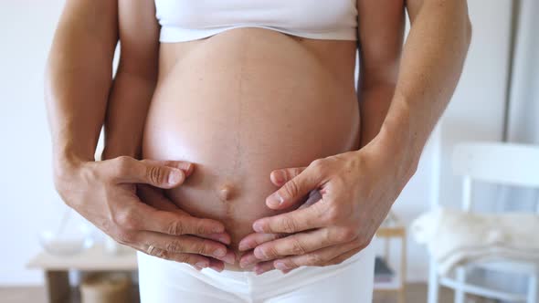 Pregnant Woman And Her Husband Hugging Tummy With Hands Together